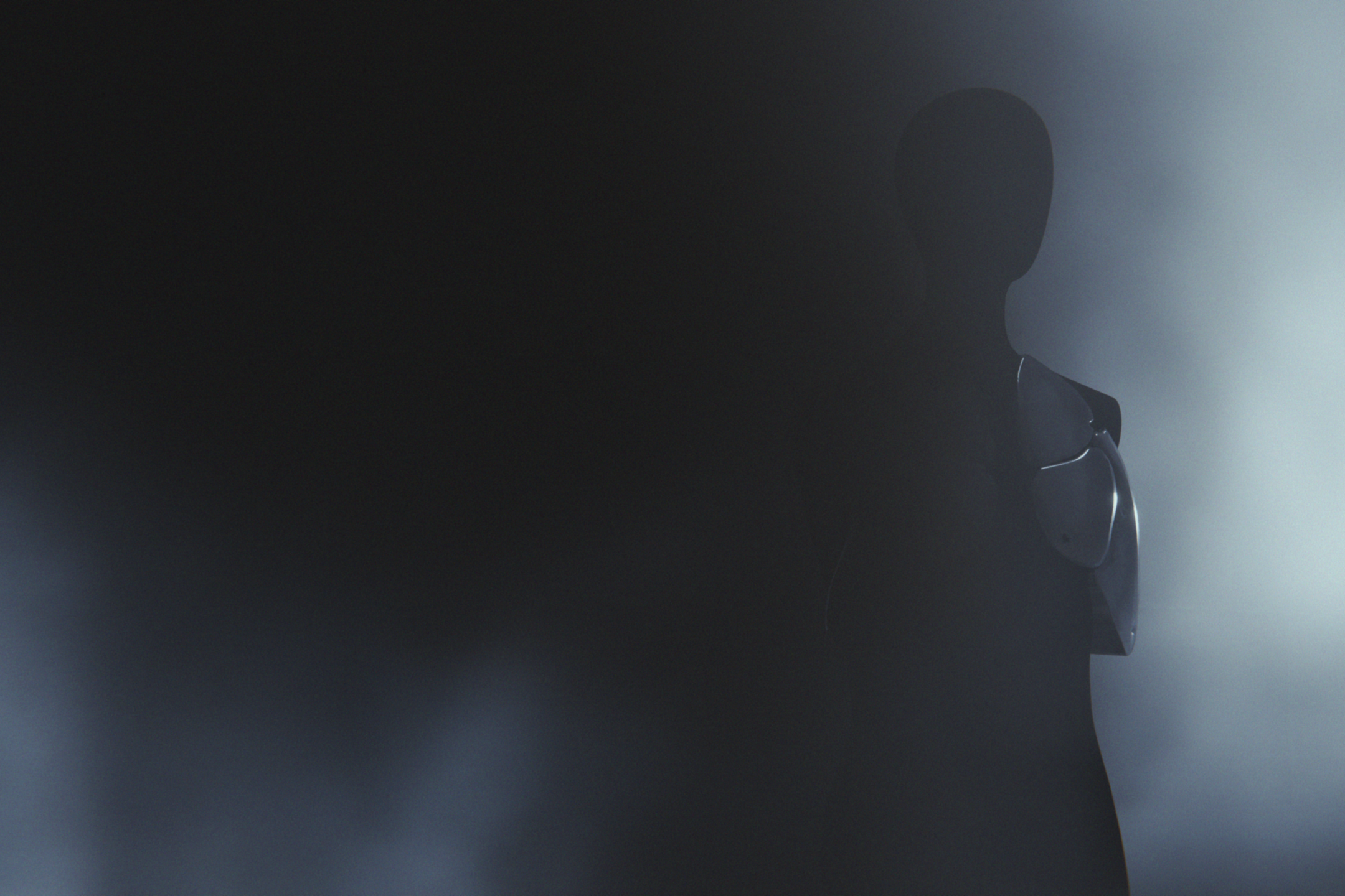 schemenhafte Person hinter einer grau-blauen Wand