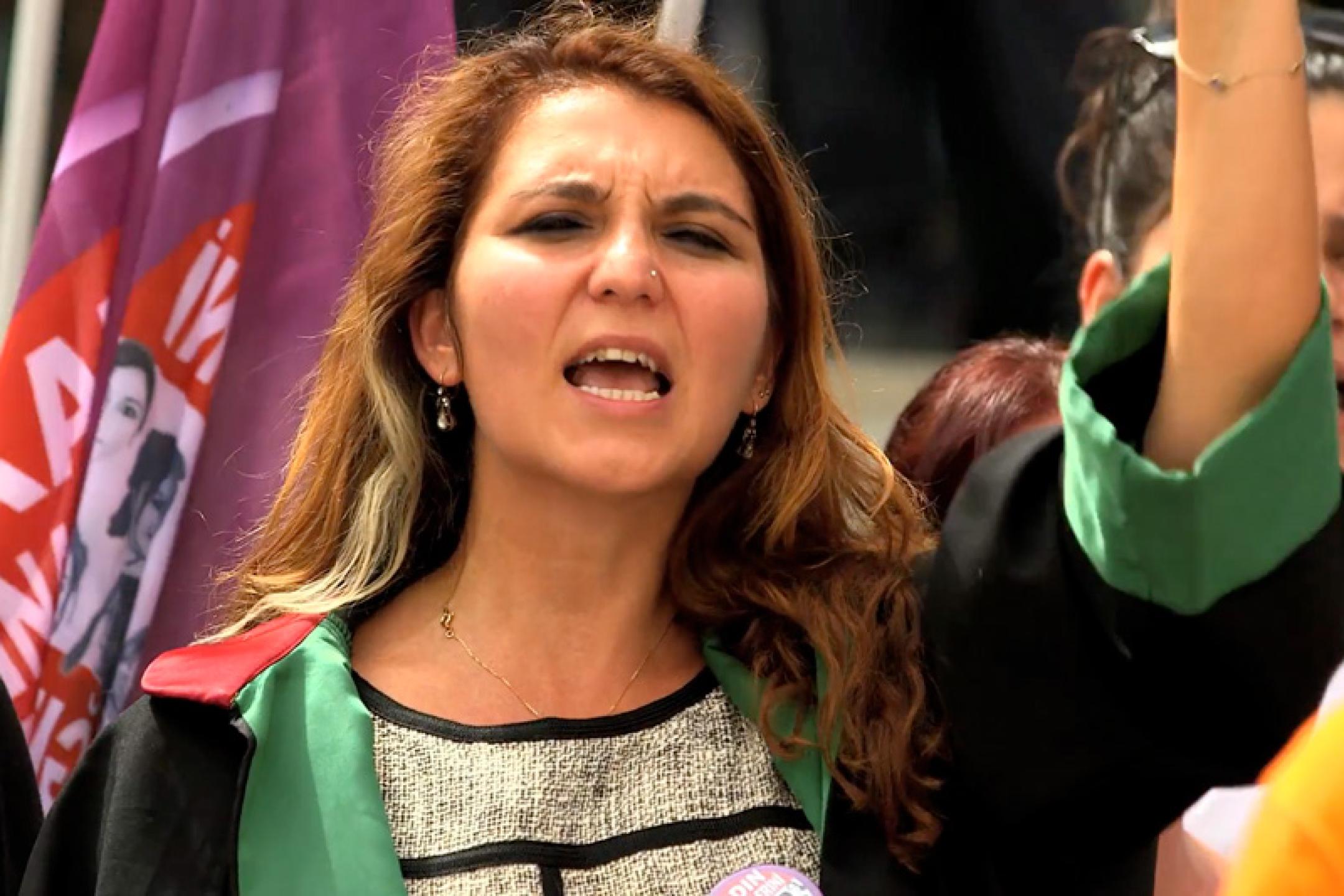 A woman with long hair is shouting at a protest march.