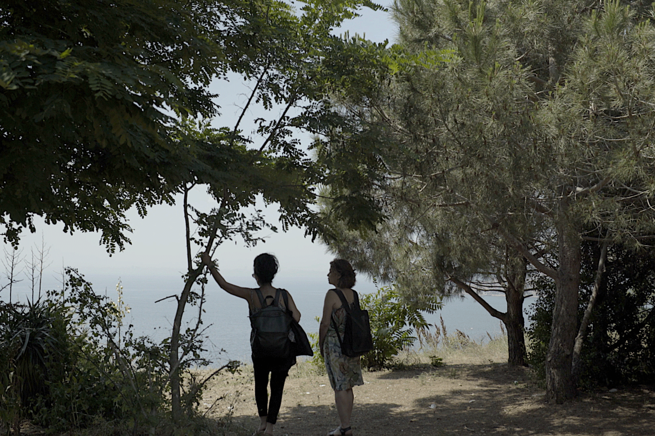 Two women stand on a (river)bank an look out on the water.