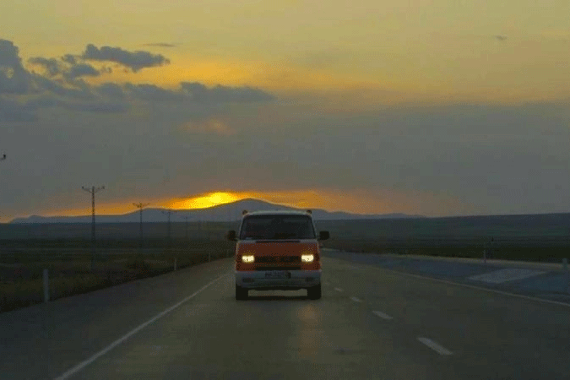 A van driving on a street in a empty landscape.