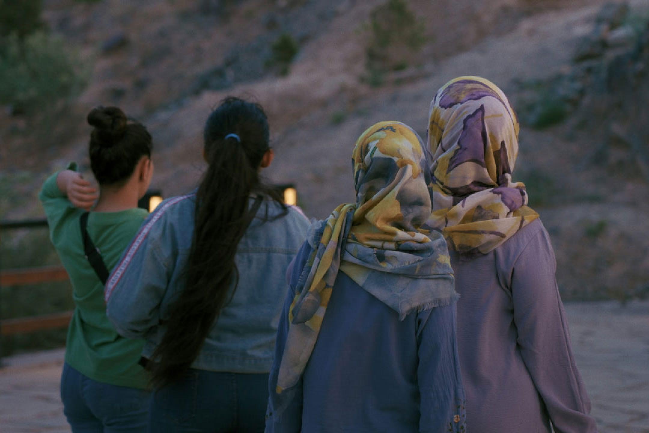 Four women stand together looking at a landscape at dawn.