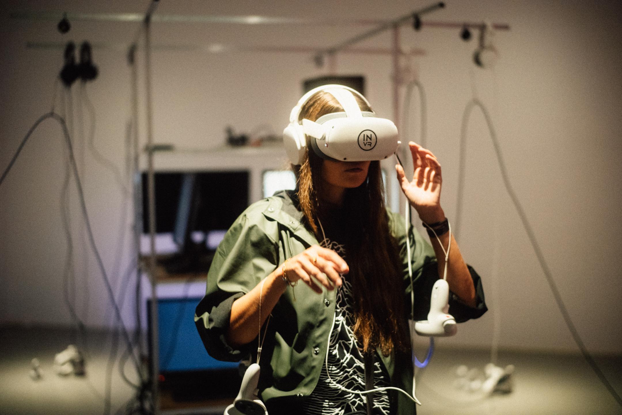 A woman wearing vr glasses is raising her hands to the machine