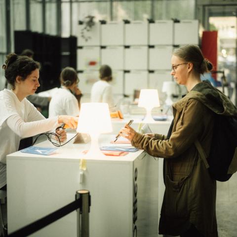 Ein Volunteer im Gästebüro checkt einen Gast ein.