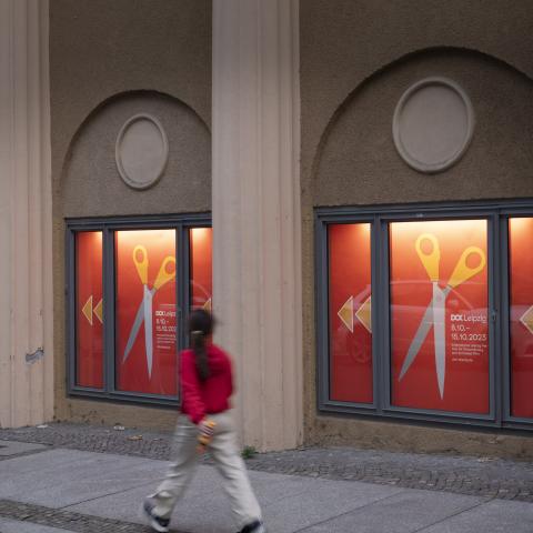 Eine Person läuft an Festivalplakaten im Kinofenster vorbei.