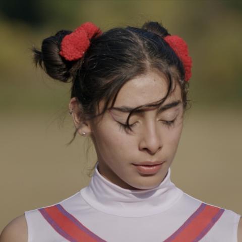 Ein Filmstill eines Mädchen mit zwei Dutts auf ihrem Kopf, sie hat die Augen geschlossen und ihr Pony weht im Wind