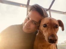 A portrait of Lucy Mukerjee with a honey-coloured dog 