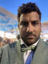 Portrait of Inney Prakash in a gray suit and a green bow tie