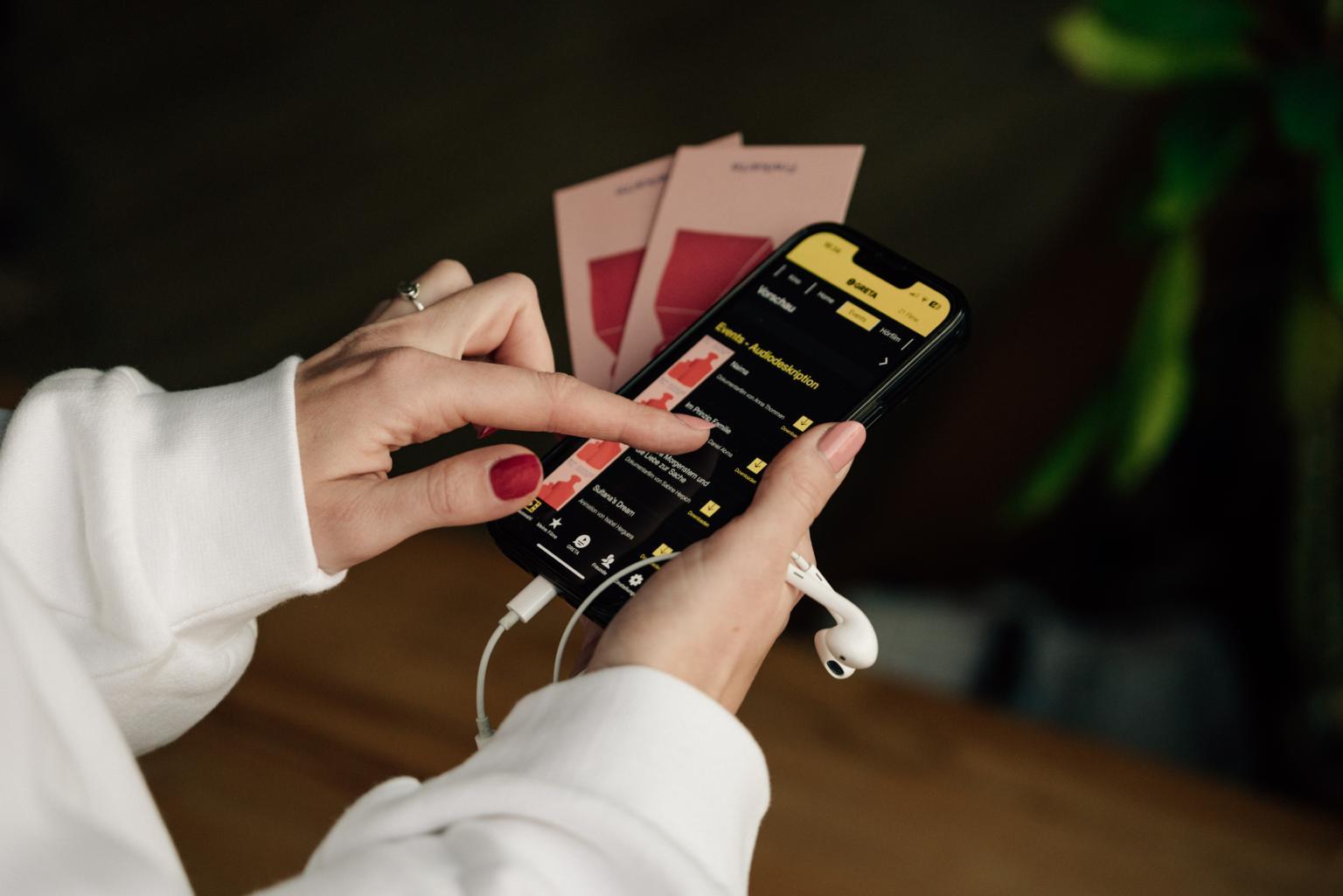 Close-up of hands holding a mobile phone with the Greta app for audio description open